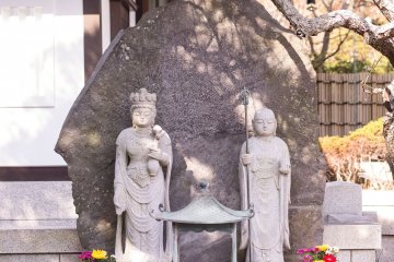 Two stone deities stand before the temple gates, ready to hear your prayers