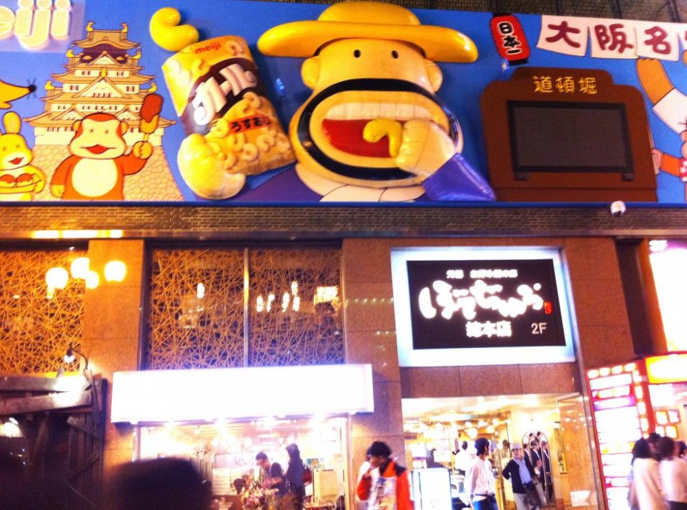 Oversized Cartoon Characters like Popcorn man lure us into a night fantasy that is adult and childlike at the same time at Dotonbori
