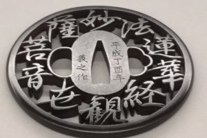 A tsuba with a verse from Buddhist scripture