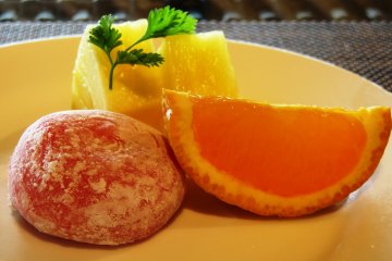 A trio of strawberry mochi rice cake accompanied by pineapples and orange slice
