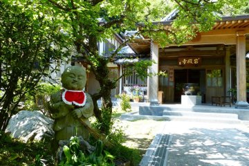 Jizo statue sweeping the garden with a broom