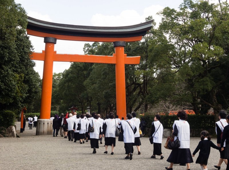 Group of Japanese pilgrims passing under the first torii; there will be many more gates ahead