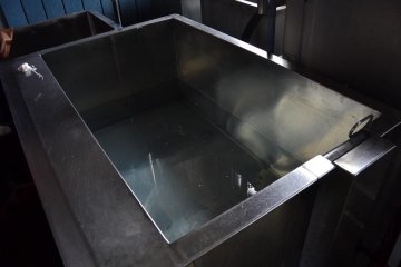 An aluminum vat that is used for washing away rice glue on dyed fabric.