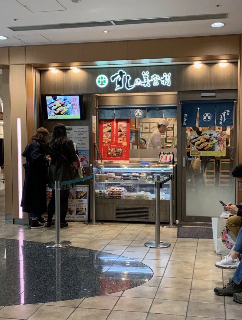 The front of Sushi no Midori.  Note the two customers at the left where the ticketing machine is located to get your serving number
