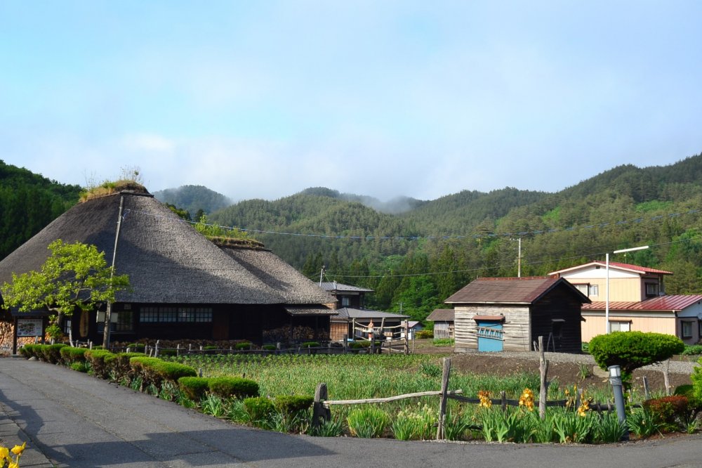 The quiet and peaceful museum surrounded by fields and mountains. In the distance a yamase makes it way across the forest, carried from the sea in the distance.
