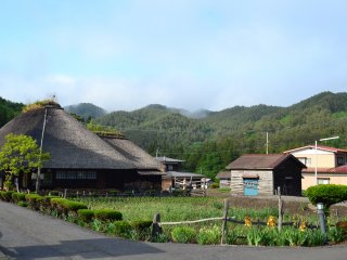 The quiet and peaceful museum surrounded by fields and mountains. In the distance a yamase makes it way across the forest, carried from the sea in the distance.