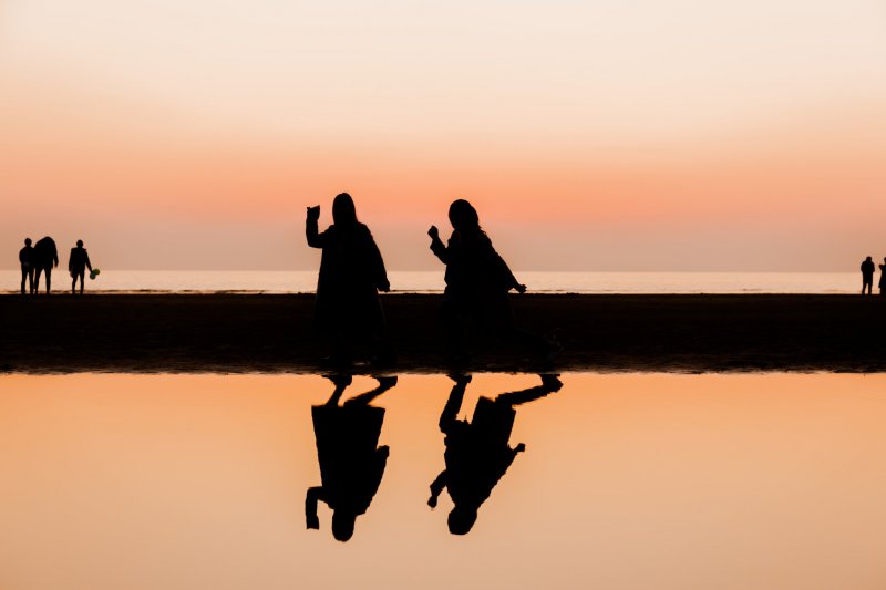 The setting sun turns these young girls into orange-hued silhouettes 