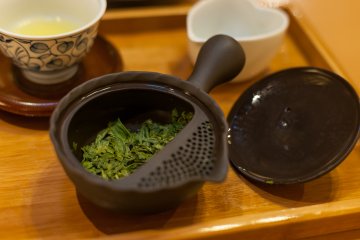 Чайник для заварки и мягко поблескивающие листики чая