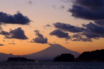 Гора Фудзи находится достаточно далеко, НО, в удачно подобранный момент, ее силуэт как будто возвышается над вами и заполняет собою небо. 