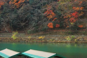 <p>เรือที่จอดในแม่น้ำโฮะซุกะวะ (Hozugawa) ที่มีสีเขียวมรกตและสีสันของฤดูใบไม้ร่วง</p>