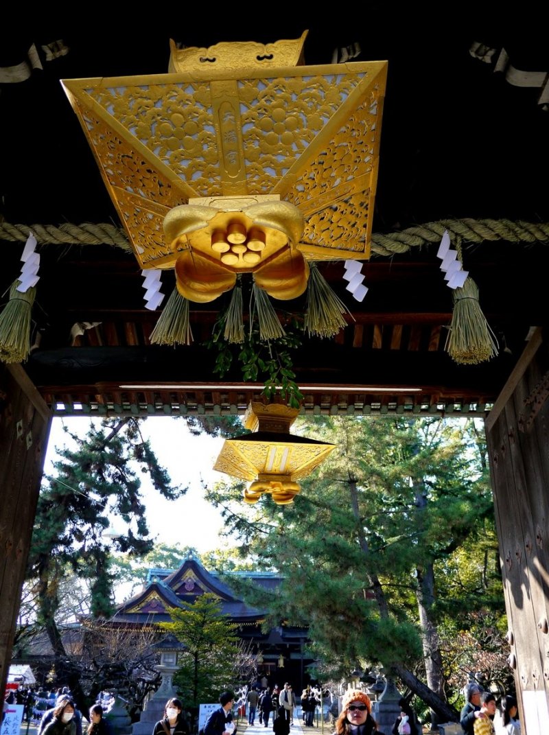 <p>Ornate gold lanterns hang from the ceiling of the entrance gate</p>